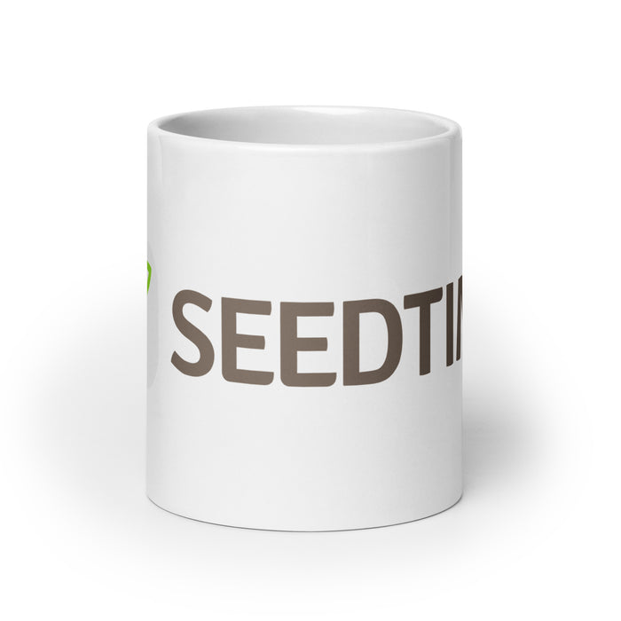 White ceramic coffee mug with brown 'SEEDTI' text and a vibrant green sprout design.