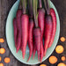 Vibrant heirloom purple and red carrots on a green plate. Sliced orange carrots on rustic wood.