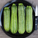 Four fresh striped green zucchini on a black plate with a knife. Healthy garden vegetables for home cooking.