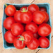 Vibrant red cherry tomatoes in a blue berry carton, fresh garden produce on a rustic wooden surface.