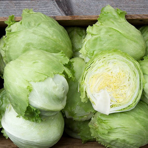 Crisp iceberg lettuce heads, one sliced, in a wooden crate. Fresh green vegetable for salads.