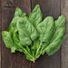 Fresh green spinach leaves with water droplets on a rustic dark wood background. Healthy leafy vegetable produce.