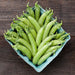 Fresh green sugar snap peas in a blue market carton on a dark wood background. Healthy organic spring vegetables.