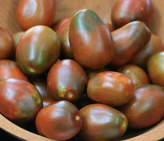 Bowl of ripe black heirloom tomatoes, dark red with green shoulders. Fresh garden produce.