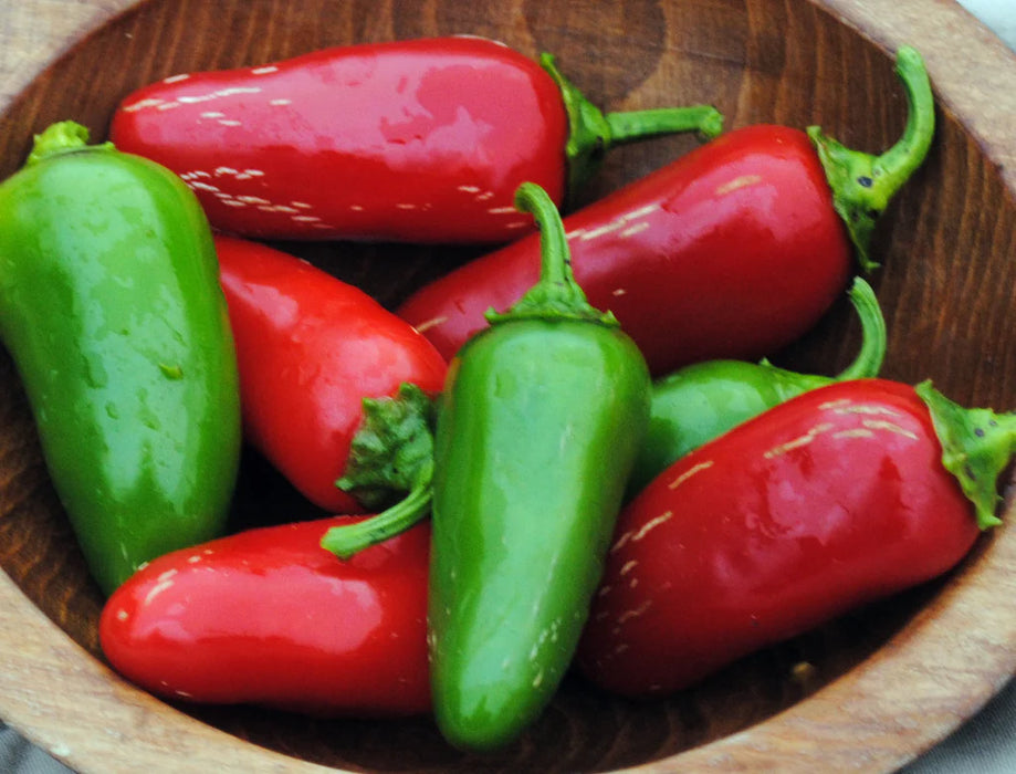 Red and green jalapeño peppers in a wooden bowl. Fresh, vibrant, and spicy chili peppers.