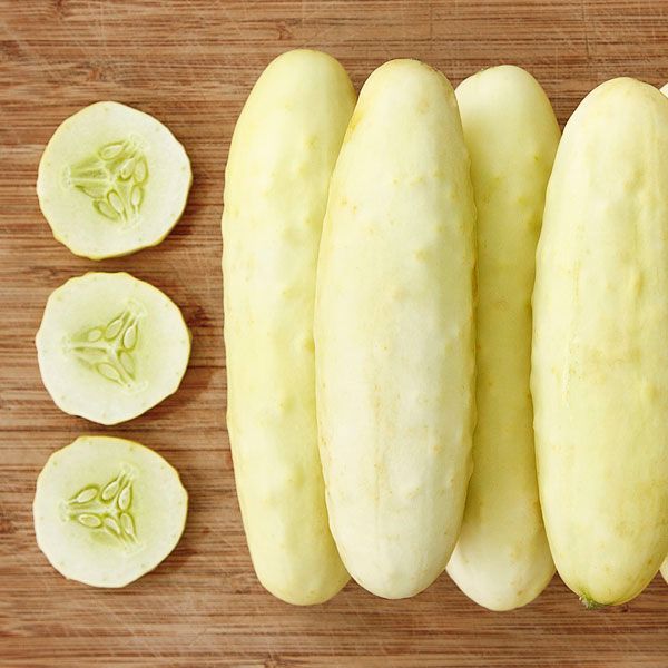 Fresh pale yellow cucumbers, whole and sliced, on a wooden cutting board. Healthy vegetables.