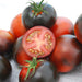 Fresh black heirloom tomatoes, one sliced to reveal red flesh and seeds.