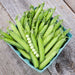 Basket of fresh garden pea pods, one opened to show bright green peas, on a rustic wooden background.
