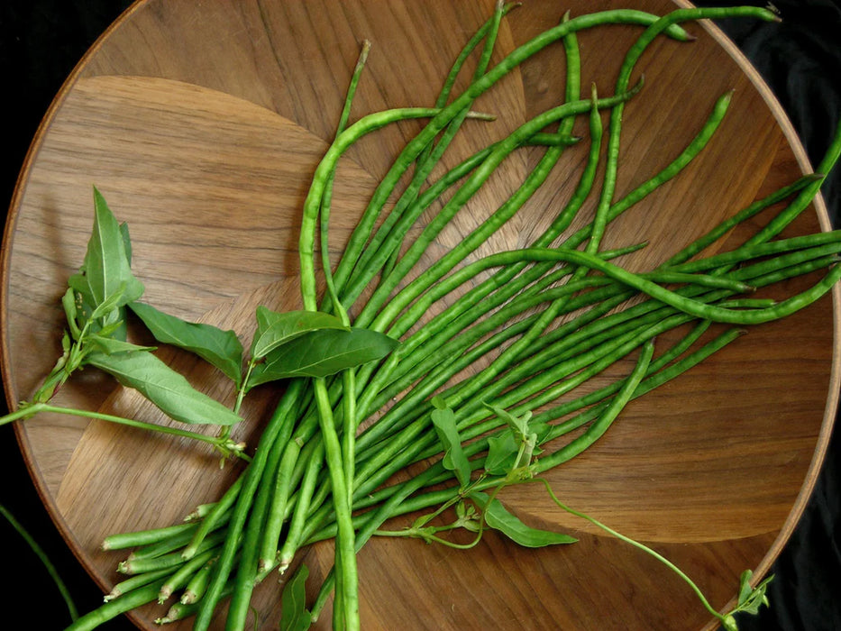 Fresh green yardlong beans and leafy greens in a decorative wooden bowl. Healthy Asian vegetables.