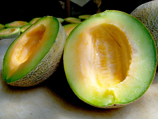 Ripe cantaloupe melon cut in half, revealing bright orange flesh and green rind. Fresh, healthy fruit slices.