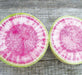 Watermelon radish halves with vibrant pink and white interior, green skin, on weathered wood.
