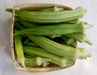 Fresh green okra pods in a rustic wooden basket. Healthy produce for cooking.