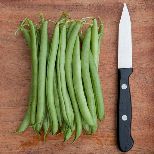Vibrant green beans piled beside a sharp kitchen knife on a rustic wooden cutting board for fresh vegetable prep.