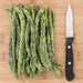 Fresh Dragon Tongue beans piled on a wooden cutting board next to a sharp kitchen knife. Heirloom green beans.