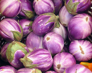 Basket filled with small, round purple and white striped eggplants (fairy tale eggplants) with green caps.