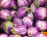 Basket filled with small, round purple and white striped eggplants (fairy tale eggplants) with green caps.