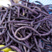 Fresh purple green beans piled high on a blue checkered cloth. Healthy, vibrant farmers market produce.