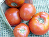 Fresh, ripe red garden tomatoes spilling from a rustic basket.