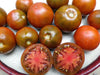 Fresh black heirloom tomatoes, whole and sliced, revealing dark red flesh.
