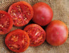 Fresh ripe red tomatoes, whole and sliced, with visible seeds on burlap. Healthy garden produce.