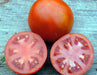 Ripe red tomato, whole and sliced, showing juicy pink flesh and seeds. Fresh garden produce.