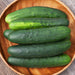 Fresh green cucumbers with bumpy skin in a rustic wooden bowl. Healthy garden vegetables, crisp produce.
